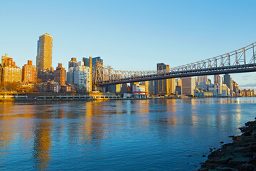 Sunrise over Manhattan in New York City, USA. Skyline illuminated by rising sun with reflection in river.