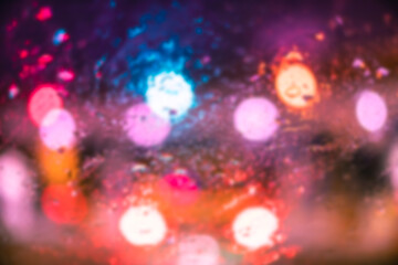 Obraz premium Abstract bokeh blur background by rain drops on glass window at night in the city