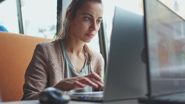Young ptretty woman using portable laptop computer. Female freelancer or student typing keyboard, texting or coding, working at modern light workplace
