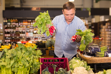 Portrait of man buying radish for salad in supermarket