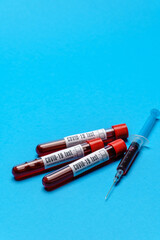 Syringe And Plastic Test Tube With Blood Sample over blue background with copyspace