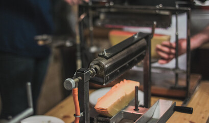 Detail of a raclette heater. Gourmet food being prepared under a gas heater above cheese.