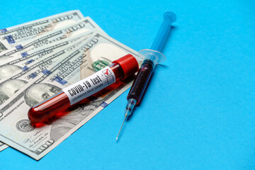 Close up 100 US dollar bills and blood sample in test tube over blue background