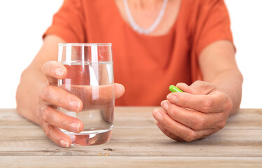 Old people holding a glass of water in one hand and medicine in the other hand in front of white background