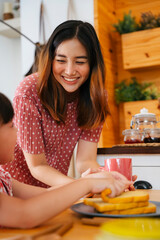 Mother prepare bread toast for breakfast to her child at home.