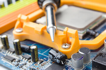 Fototapeta premium soldering iron on the background of a computer Board and capacitors in soft focus.