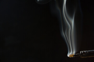 Heated soldering iron with smoke from the sting of burning rosin. Photo on a black background
