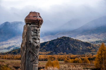 Wooden totem pillar on mountains background in autumn. Orthodox old believers totem. Religious...