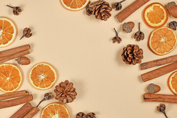 Fototapeta na wymiar Seasonal autumn flat lay with natural dried orange slices, cinnamon sticksand fir cones on beige background with empty copy space