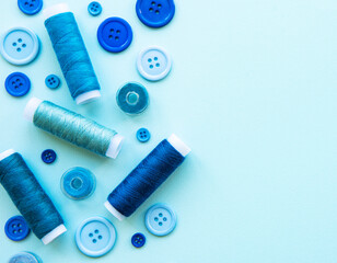 Fototapeta na wymiar Spools of thread and buttons in blue tones on a blue background
