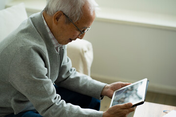 タブレットPCでテレビ電話をする日本人シニア男性 © arc image gallery