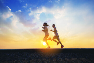 Young couples running sprinting on road. Fit runner fitness runner during outdoor workout with sunset background.