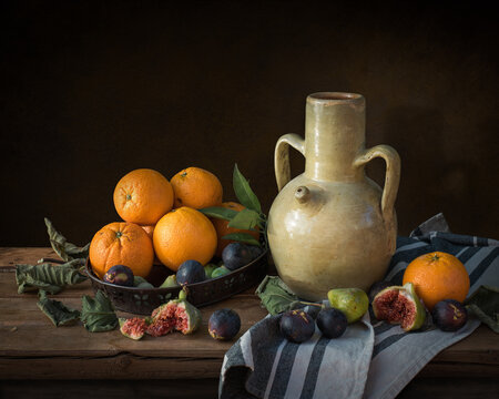 Still life in Spanish style with a clay jug, oranges, and figs