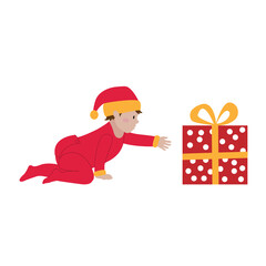 Christmas. A cute little baby in a red overalls and a santa claus hat is reaching for a Christmas present.