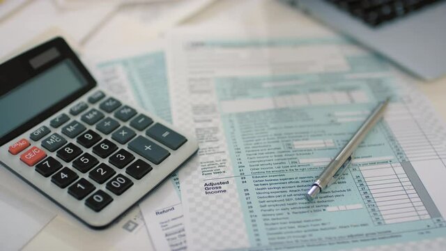 From above flat lay stab closeup of printed tax return form with calculator lying at coffee table