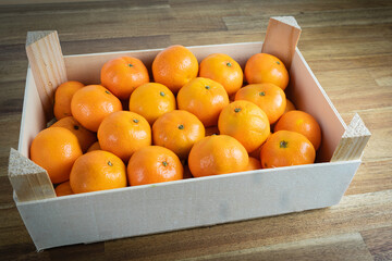 A wooden box with many tangerines - 390054616