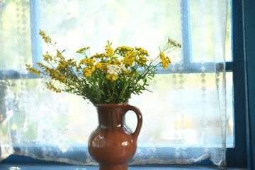 A bouquet of wildflowers in a clay jug on the veranda window. Retro vintage photos. Delicate soft selective focus. The atmosphere of a summer country house.
