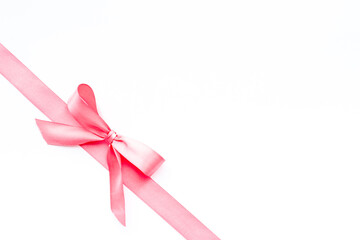 Pink ribbon with bow isolated on white. Top view, copy space