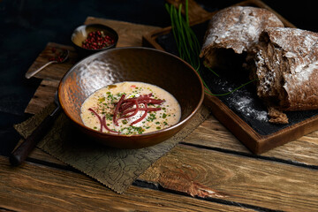 Traditional Italian soup with barley and bresaola on old wooden background. Selective focus. Dark tone.