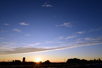 夜明けの空に現れた龍のしっぽのような鱗雲。空を二分する巻積雲。朝焼け。空の背景素材