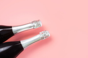 Neck of a champagne bottles with silver foil on a pastel pink background. The concept of a...