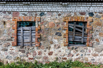 Fototapeta na wymiar Two windows in an old building boarded up by boards