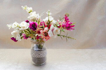 Close-up of gentle floral compositions in vases on the beige background