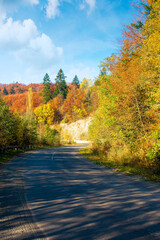 Obraz premium old serpentine road in mountains. beautiful autumn scenery on a sunny day. trees in colorful foliage. countryside journey on a weekend concept