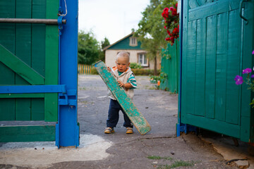 the child closes the gate of the yard in the village