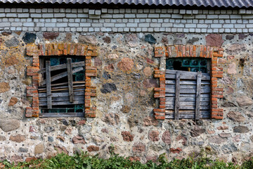 Two windows in an old building boarded up by boards