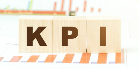 letters kpi on wooden cubes on desk with different graphs