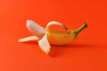 Fresh yellow half peeled banana on screaming red background