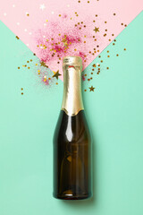 Bottle of champagne and glitter on mint background