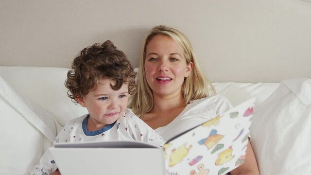 Mother reading bedtime story to son wearing pyjamas before going to sleep - shot in slow motion