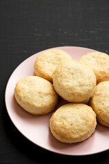 Homemade Flaky Buttermilk Biscuits on a pink plate on a black surface, low angle view. Copy space.