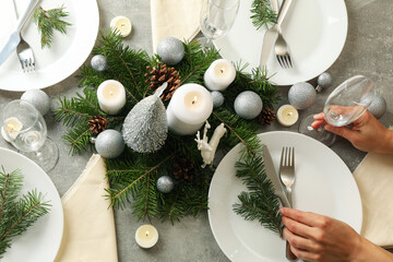 Woman is engaged in setting New Year's table on a gray table