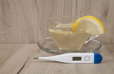 Lemon tea and medical  thermometer on a wooden background.