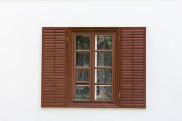 Window with brown wooden shutters and white wall