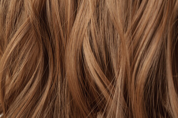 close up of multiple pieces clip in brown wavy synthetic hair extensions 