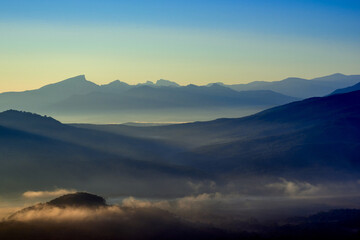 Fototapeta na wymiar Mountain valley covered with fog and illuminated by the morning sun