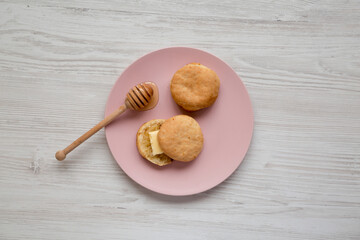 Homemade Flaky Buttermilk Biscuits on a pink plate on a white wooden table, top view. Flat lay, overhead, from above.