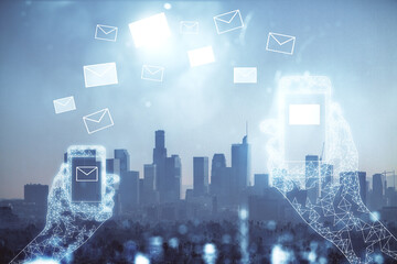 Double exposure of envelop hologram flying from gadget and city view background. Concept e-mail.