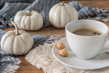 Cup of coffee, woolen scarf and mini white pumpkins on oak wooden floor, cozy coffee break concept