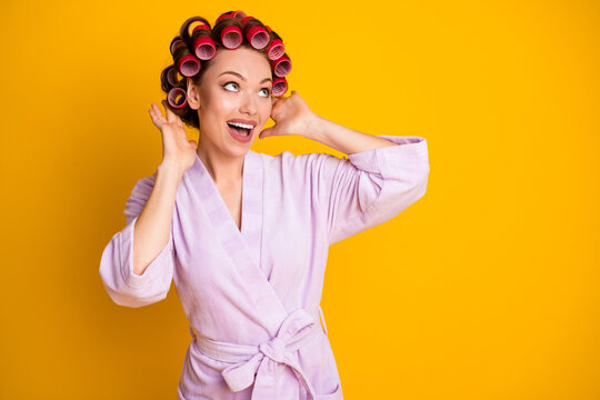 Portrait of lovely glamorous cheerful woman wearing fixing curlers enjoying good mood isolated bright yellow color background