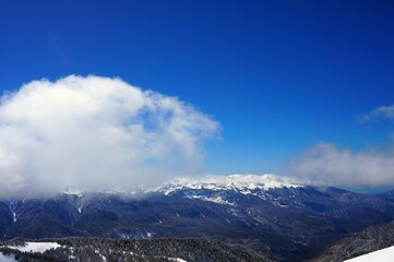 Beautiful winter landscape in the mountains, deep snow, blue sky, ski slopes, winter forest, snow-capped mountain peaks.