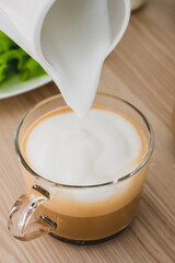 The milk foam is pouring into the coffee.