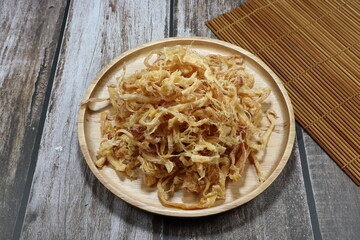 Baked dried shredded squid on the wooden plate. Famous traditional seafood snack in Asia party.