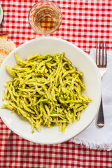 Top view of dinner table with a bowl of pasta pesto genovese, blurred background. Selective focus - shallow depth of field.