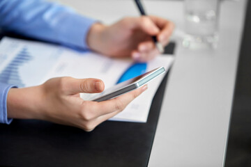 Fototapeta premium business, technology and people concept - close up of businesswoman using smartphone at office