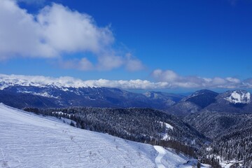 Fototapeta na wymiar Beautiful winter landscape in the mountains, deep snow, blue sky, ski slopes, winter forest, snow-capped mountain peaks.